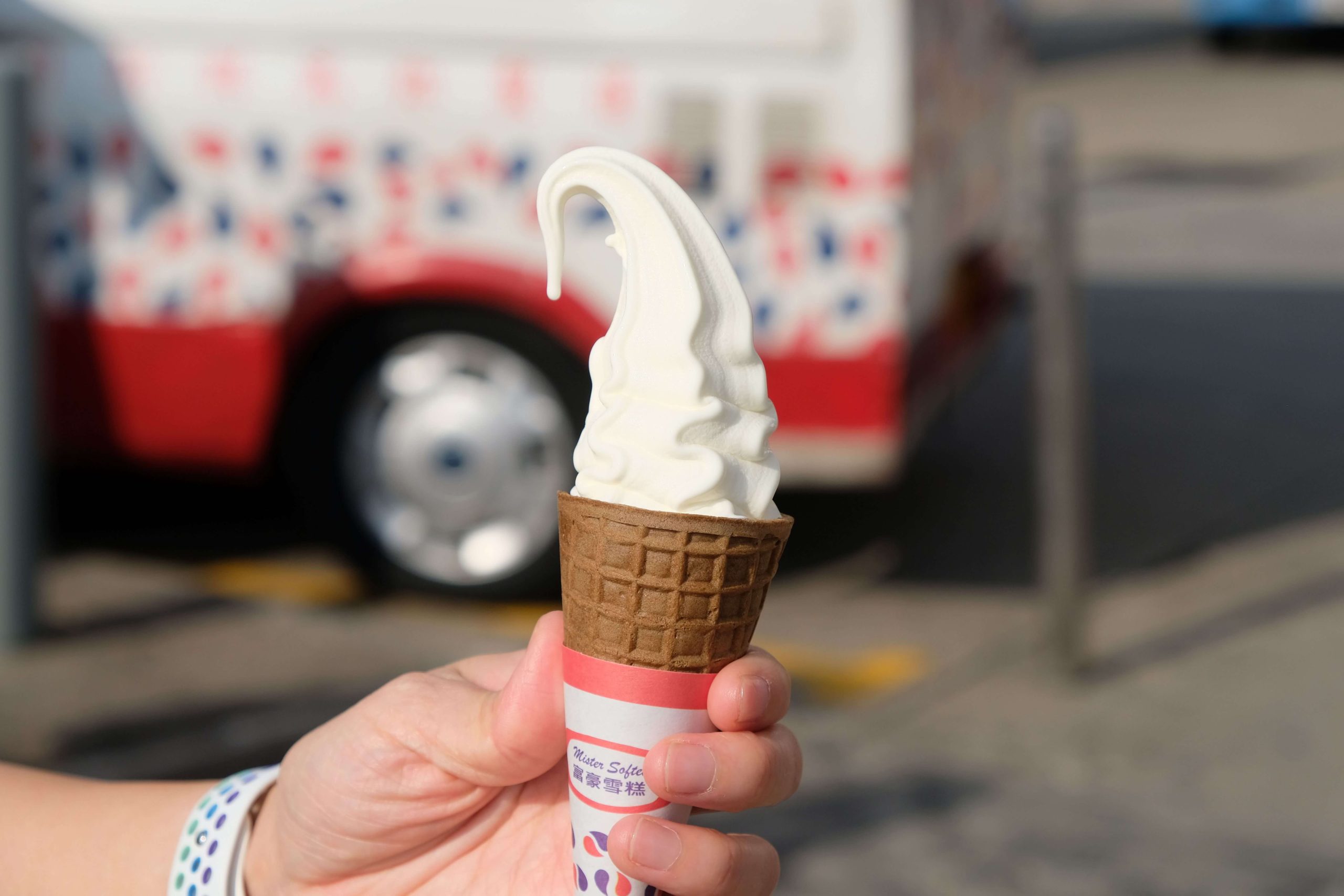 Countertop ice cream machine serving a smooth vanilla soft serve ice cream cone in a waffle cone.